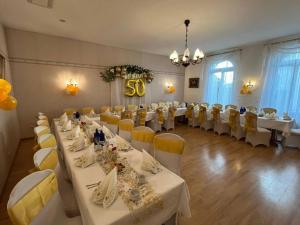 a banquet hall with white tables and yellow chairs at Hotel-Restaurant Alt Karow in Berlin