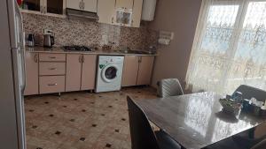 a kitchen with a washing machine and a table at Gohar Bed and Breakfast in Tatʼev