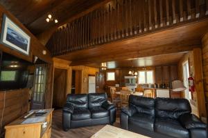a living room with leather furniture and a kitchen at Chalets Gallix in Sept-Îles