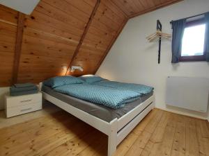 a bed in a room with a wooden ceiling at Chata Vedle Jedle in Dolní Morava
