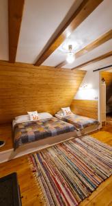 a bedroom with two beds and a large rug at Căsuța cu Alune in Rîmeţi-Valea Uzei
