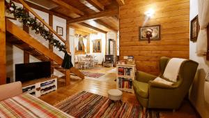a living room with a staircase and a chair and a television at Căsuța cu Alune in Rîmeţi-Valea Uzei