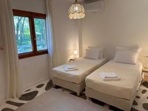 two twin beds in a room with a window at Villa Ethel Vourvourou in Vourvourou
