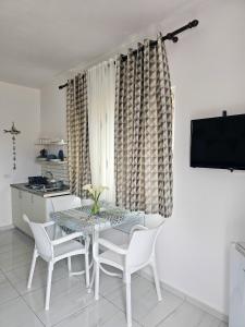 a dining room with a table and chairs and a television at Troi beach house in Vlorë