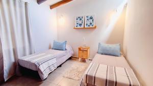 two twin beds in a room with a window at La Isolina Chacras, jardín, parrilla y naturaleza! in Chacras de Coria