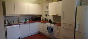 a kitchen with white cabinets and a white refrigerator at Eina house near the E4 road in Eina
