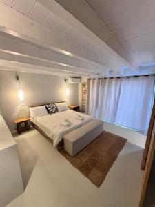 a bedroom with a large bed and a large window at Lucié in Argyrátika