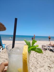 a person holding a drink on the beach at SecretVilla in Ghār al Milḩ