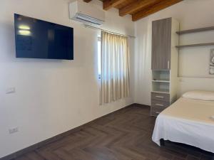 una camera da letto con un letto e una TV a parete di Madomare Case al Mare a Lampedusa