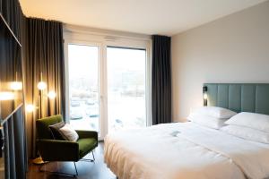 a bedroom with a bed and a chair and a window at SOLLER Business Hotel - Munich Airport MUC in Hallbergmoos +62 photos
