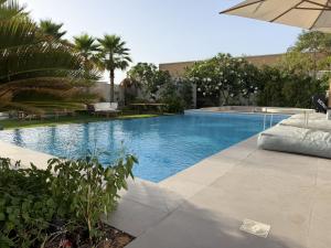 a swimming pool with an umbrella next to a resort at Villa 72 RAK in Ras al Khaimah