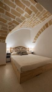 ein Schlafzimmer mit einem Bett vor einer Ziegelwand in der Unterkunft Arkea in Trapani
