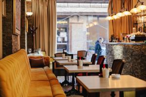 ein Restaurant mit Tischen, Stühlen und einer Couch in der Unterkunft Garni Hotel Planeta Inn in Novi Sad + 43 Fotos