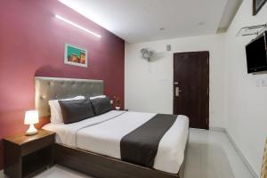 a bedroom with a bed and a red wall at Collection O Lotus Grand in Hyderabad