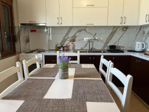 a kitchen with a table and chairs and a kitchen with white cabinets at Andrew's place in Metogjashta