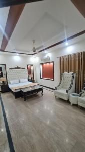 a living room with a bed and two chairs and a table at Classy home in Lahore