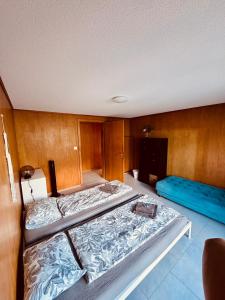 a room with two beds and a blue couch at Chalet Luna - Alpine Apartment by Lake Brienz in Niederried
