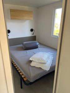 a bedroom with a bed with a pillow and a window at Camping Carnac in Carnac