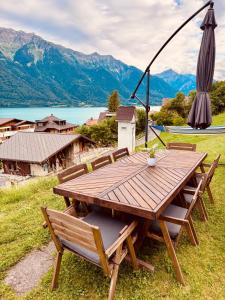 a wooden picnic table with chairs and an umbrella at Chalet Luna - Alpine Apartment by Lake Brienz in Niederried