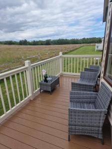 a deck with four chairs and a vase with flowers at Riley's Caravan sand le mere tunstall view in Tunstall