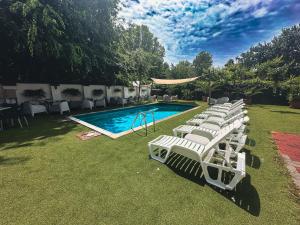 a row of white lounge chairs next to a swimming pool at Hullam Rooms Siofok in Siófok