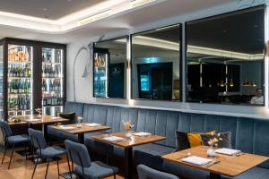 a restaurant with wooden tables and chairs and windows at SOLLER Business Hotel - Munich Airport MUC in Hallbergmoos