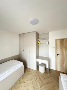 a white bedroom with a bed and a desk at J&M apartman in Liptovská Teplá