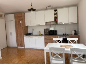 a kitchen with white cabinets and a table and chairs at Apartment Centar Sarajevo in Sarajevo