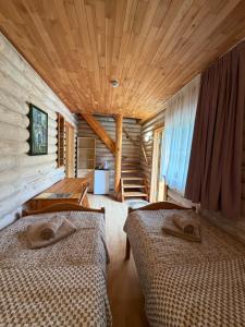 a bedroom with two beds in a log cabin at Karolio Sodyba Palūšėje in Palūšė
