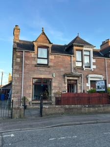 a brick house with a red fence in front of it at Tay Villa in Inverness