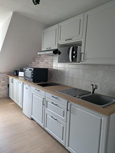 a kitchen with white cabinets and a sink at L'industriel in Sarreguemines