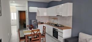 a kitchen with white cabinets and a table and chairs at Kaza Branka in Sal Rei