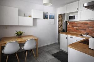 a kitchen with white cabinets and a wooden table and chairs at RosalieRose Cozy Corner in Radom