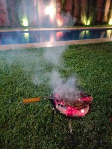 a bbq grill with smoke in the grass at Villa Nono & Zac Marrakech in Ourika