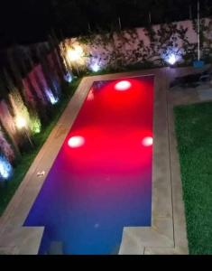 a pool with red and blue lights in a yard at night at Villa Nono & Zac Marrakech in Ourika