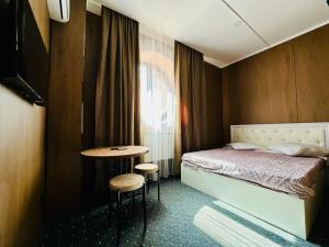 a bedroom with a bed and a table and a window at Гостиница Желкен in Aktobe
