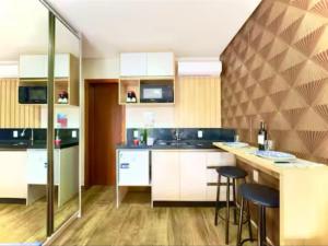 a kitchen with white cabinets and bar stools at Studio moderno com piscina 350m do mar in Piçarras