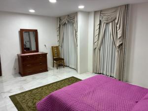 a bedroom with a purple bed and a dresser and a mirror at Garsol in Oruro
