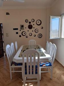 a dining room table with white chairs and a table and a wall at Spacious Villa-walking to beach in Marsa Matruh