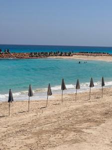 a group of umbrellas on a beach with the ocean at Spacious Villa-walking to beach in Marsa Matruh