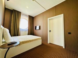 a bedroom with a bed with a table and a door at Гостиница Желкен in Aktobe +14 photos