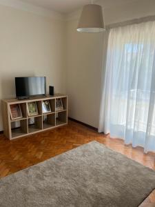 a living room with a flat screen tv on a stand with a window at City Centre Cozy Apartment in Porto