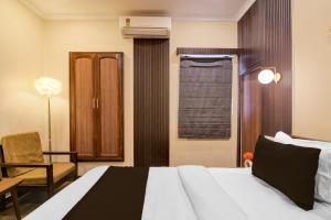 a bedroom with a bed and a chair and a window at Collection O Lake Mall Kalighat Formerly Venkateshwara in Kolkata
