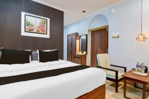 a bedroom with a large white bed and a desk at Collection O Lake Mall Kalighat Formerly Venkateshwara in Kolkata