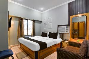 a bedroom with a large bed and a chair in it at Collection O Lake Mall Kalighat Formerly Venkateshwara in Kolkata