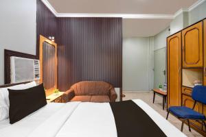 a bedroom with a bed and a chair and a couch at Collection O Lake Mall Kalighat Formerly Venkateshwara in Kolkata +24 photos