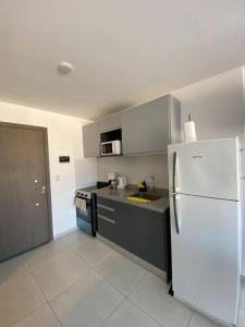 a kitchen with a white refrigerator and gray cabinets at Monoambiente Cipolletti in Cipolletti