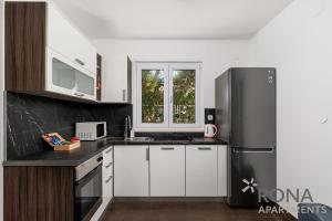 a kitchen with white cabinets and a stainless steel refrigerator at Rona Apartments Zlatko in Šimuni