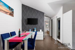 a dining room with a pink table and blue chairs at Rona Apartments Zlatko in Šimuni