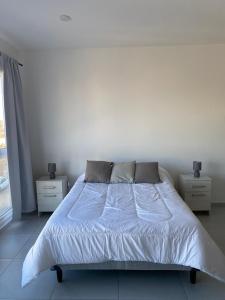 a bed in a white room with two night stands at Monoambiente Cipolletti in Cipolletti